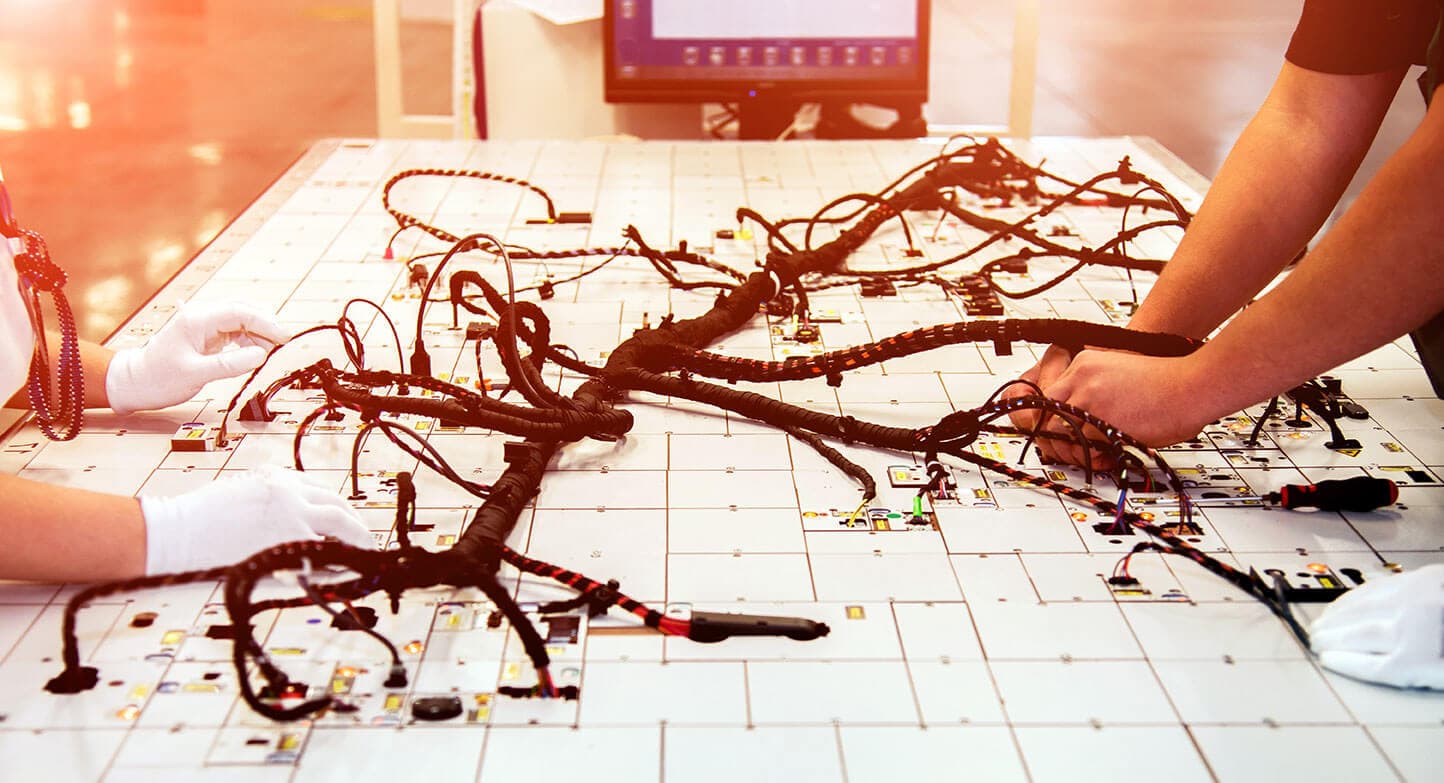 A wiring harness being assembled by hand on a production board